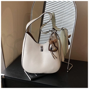 Detail of cream white hobo bag featuring silver twist lock and leopard print heart charm