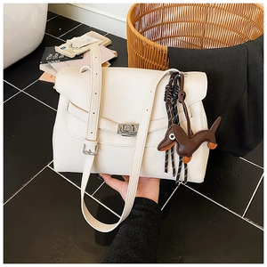 Close-up of white lychee texture tote bag with metal lock and cute dog charm detail