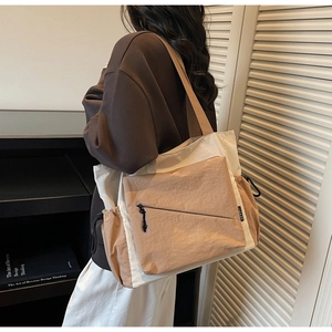 Detail of canvas tote bag showing side drawstring and khaki nylon zipper pocket