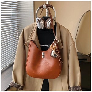Close-up of caramel bucket bag with silver twist lock and leopard print heart charm