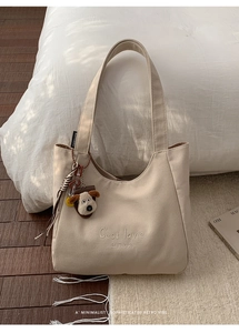 Detail of beige canvas tote bag featuring C'est lavie embroidery and cute puppy charm