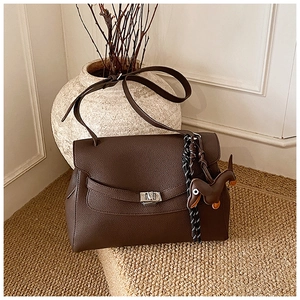 Detail of dark brown lychee leather tote bag with silver twist lock and dog charm decor