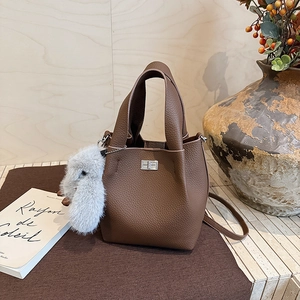 Detail of brown litchi pattern leather bucket bag with silver lock and plush bunny