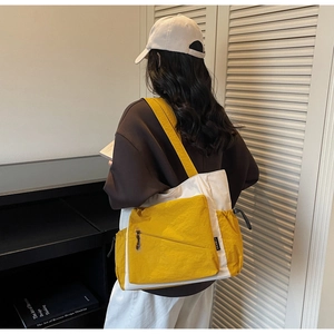 Detailed side view of two-tone nylon tote bag with drawstring pocket and front zipper