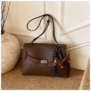 Macro detail of dark brown lychee leather texture and silver twist lock on tote bag