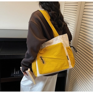 Detail of a large color-block tote bag in bright yellow and cream with zip pocket