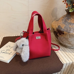 Detail of red leather bucket bag featuring silver lock and grey rabbit fur charm accessory