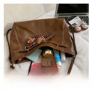Detail view of large brown tote bag showing spacious interior with tablet and cosmetics