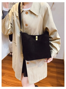 Close-up of matte black suede bucket bag featuring a premium gold twist lock buckle