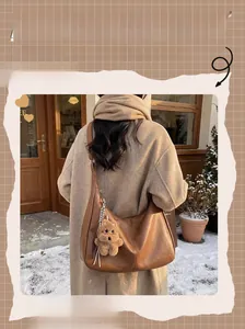 Brown oversized winter tote bag with cute bear charm shown in a snowy street style scene