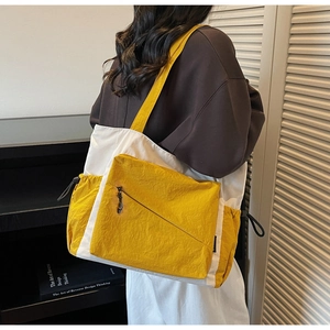 Detail of yellow and white nylon tote bag with large zipper pocket and wide shoulder strap