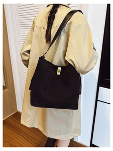 Detail of minimalist black matte suede bucket bag with elegant golden rotating lock