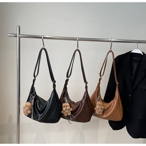Detailed view of three minimalist crescent shoulder bags in black, coffee and caramel