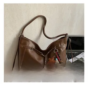 Detail view of large dark brown leather tote with white stitching and cartoon charms