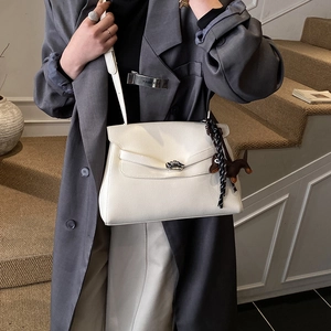 Detail view of white lychee leather handbag with silver lock and dachshund charm
