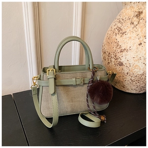 Détail du sac seau vert avec texture en tweed et pendentif pompon en peluche marron