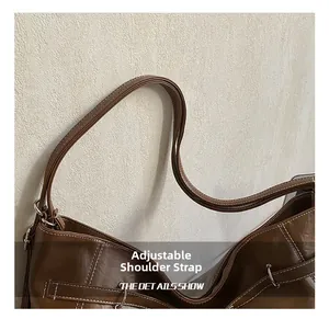Detail of adjustable leather shoulder strap with silver metal buckle and refined edge finish