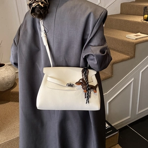 Detail of white lychee leather handbag with silver lock and dog charm on a model