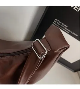 Macro shot of dark brown leather shoulder bag with adjustable silver metal square buckle