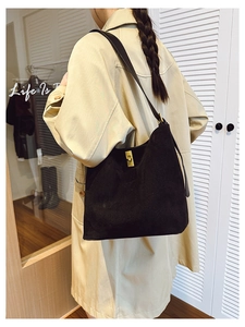 Detail of black suede shoulder bag with gold twist lock worn with a khaki trench coat