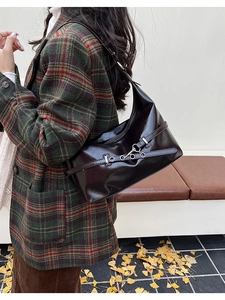 Détail du sac sous le bras en cuir verni marron avec chaîne sur un banc d'automne