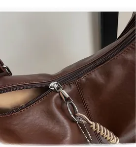 Detail of smooth metal zipper and woven puller on a brown vintage leather shoulder bag