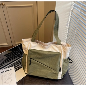 Detail of multi-pocket tote bag with olive green accents and diagonal zipper pocket