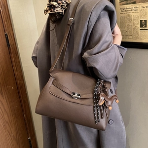 Detailed view of brown lychee grain leather tote bag with silver buckle on a model