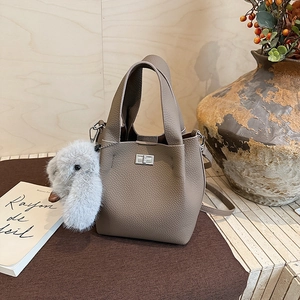 Detail of taupe pebbled leather bucket bag with silver lock and plush bunny charm