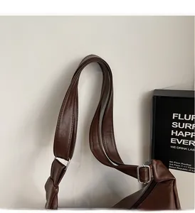 Close-up of the wide shoulder strap and silver adjustable buckle on the brown tote bag