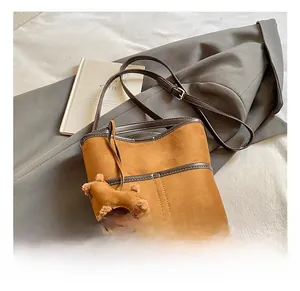 Brown suede bucket bag with dark brown leather strap and a cute teddy bear charm