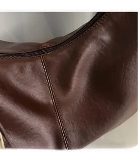 Close-up of deep brown leather texture and stitching on a large commuter tote bag