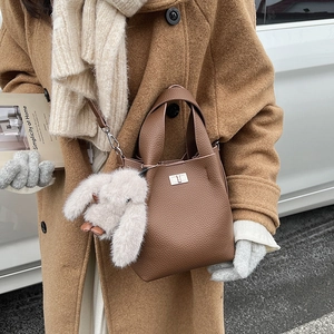 Brown lychee-texture bucket bag with silver twist lock and plush rabbit pendant