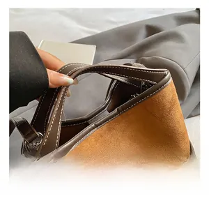 Detail of vintage brown suede bucket bag featuring contrast stitching and leather handles
