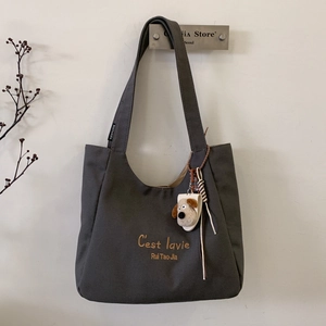 Close-up of dark grey canvas tote bag with C'est la vie text and cute dog charm