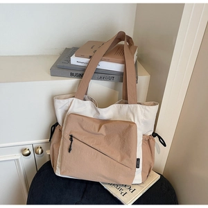 Detail of canvas tote bag showing side drawstring design and front zipper pocket