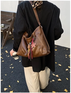 Detail of dark brown leather tote bag with white contrast stitching and cute star charms