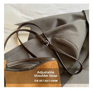 Detail of adjustable leather strap and white stitching on brown suede bucket bag