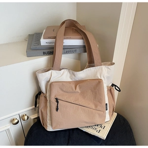 Detail of canvas tote bag showing the diagonal front zipper pocket and side drawstring pocket