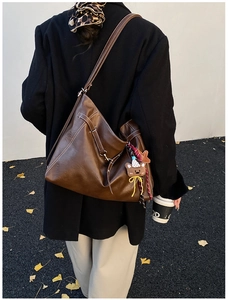 Brown leather tote bag featuring contrast stitching and a cute bear plush charm detail