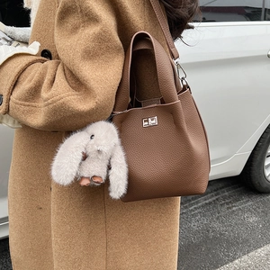 Detail of brown litchi pattern leather bucket bag with silver lock and plush rabbit charm