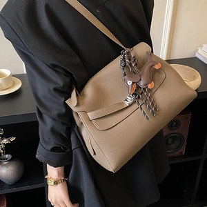 Detail of dark brown lychee leather crossbody bag with a cute dachshund dog charm