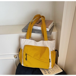 Detail of canvas tote bag with contrast yellow front zipper pocket and drawstring sides