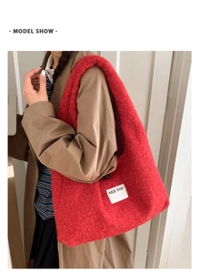 Grand sac cabas en peluche rouge avec écusson porté sur un manteau marron et rayures