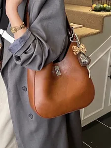 Caramel vintage leather hobo bag with metal clasp and leopard bow shown on shoulder