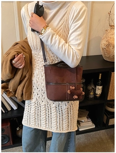 Close-up of deep brown suede bucket bag featuring contrast stitching and a plush charm