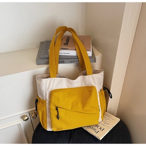 Detail of canvas tote bag with yellow zipper pocket and black drawstring side compartments