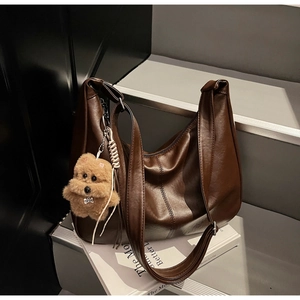 Detail of dark brown leather Hobo bag with visible stitching and plush bear charm