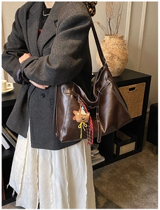 Detail of vintage brown tote bag with white stitching and plush bear charm decoration