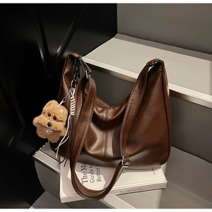 Detail of soft dark brown pebble leather tote bag with stylish plush puppy charm